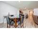 Open-concept dining area featuring a glass-top table, dark leather chairs, and wood-look floors, next to the kitchen at 3980 Gadwall Pl, Leesburg, FL 34748
