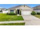 Charming single-story home with a two-car garage, beautifully landscaped lawn, and a welcoming dark blue front door at 3980 Gadwall Pl, Leesburg, FL 34748