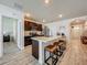 Modern open kitchen featuring a large island with seating, dark wood cabinets, stainless steel appliances, and wood-look floors at 3980 Gadwall Pl, Leesburg, FL 34748