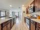 Well-lit kitchen with a center island, dark wood cabinets, stainless steel appliances, and wood-look flooring leading to the living area at 3980 Gadwall Pl, Leesburg, FL 34748
