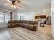 Spacious living room featuring wood-look flooring, a large sectional sofa, and an open layout with views of the kitchen at 3980 Gadwall Pl, Leesburg, FL 34748