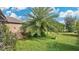 Expansive backyard with lush green grass, a mature palm tree and colorful flower beds at 5203 Jasmine Trace Ln, Kissimmee, FL 34758