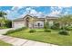 Well-maintained home featuring green lawn, mature landscaping, and solar panels on the roof, adding to energy efficiency at 5203 Jasmine Trace Ln, Kissimmee, FL 34758