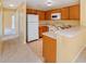 Well-lit kitchen featuring a breakfast bar, white appliances, wood cabinets, and laminate countertops at 6052 Westgate Dr # 204, Orlando, FL 32835