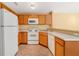Functional kitchen featuring white appliances, wood cabinetry, and a stainless steel sink with laminate countertops at 6052 Westgate Dr # 204, Orlando, FL 32835