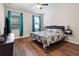 Bright bedroom features wood floors, ceiling fan, and large windows with blue curtains at 6333 Schoolhouse Pond Rd, Winter Garden, FL 34787