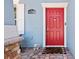 Charming red front door with a 'welcome' mat, complementing the home's exterior at 6333 Schoolhouse Pond Rd, Winter Garden, FL 34787