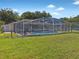 Wide backyard view of the home featuring a screened-in pool, covered patio, and storage shed at 703 Sunridge Woods Blvd, Davenport, FL 33837