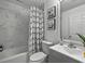 Bright bathroom with a modern white and black shower curtain, a marble-look tile wall, and a white vanity at 703 Sunridge Woods Blvd, Davenport, FL 33837