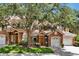 Charming townhome showcasing a stone facade, attached two-car garage, a neatly manicured lawn, and mature trees at 7521 Bay Port Rd # 12, Orlando, FL 32819