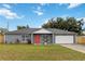 Charming single-story home featuring a gray exterior, bright red door, well-manicured lawn, and an attached two-car garage at 8 Lake Jackson Dr, Mascotte, FL 34753