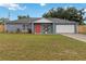 Inviting single-story home with a manicured lawn, gray exterior, and a pop of color from the red front door at 8 Lake Jackson Dr, Mascotte, FL 34753