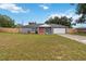 Charming single-story home featuring a gray exterior, bright red door, well-manicured lawn, and an attached two-car garage at 8 Lake Jackson Dr, Mascotte, FL 34753