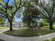 Well-manicured home featuring a two-car garage, lush landscaping, and mature trees at 809 Palmetto Ter, Oviedo, FL 32765
