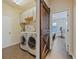 Open laundry room with front-load machines, cabinets, tile floors, and a sliding wood barn door at 809 Palmetto Ter, Oviedo, FL 32765