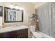 Well-lit bathroom featuring a granite countertop, dark wood vanity, and patterned shower curtain at 8652 Savory Dr, Orlando, FL 32825
