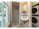 Bathroom featuring tiled shower and pedestal sink, with stacked laundry machines at 911 S Oak Ave, Sanford, FL 32771