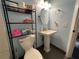 Powder blue bathroom features a pedestal sink, toilet and shelving unit for storage at 105 Wood Duck Cir # D, Daytona Beach, FL 32119