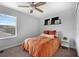 Bedroom with neutral wall, window, ceiling fan, and a bed with a vibrant orange comforter set at 11812 Metaphor Aly, Orlando, FL 32832