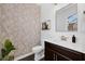 Modern powder room showcases patterned wallpaper, elegant vanity, and dark wood-style floors at 11812 Metaphor Aly, Orlando, FL 32832