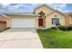 Charming one-story home featuring a two-car garage, red front door, and well-maintained lawn at 1199 Stoneham Dr, Groveland, FL 34736
