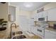 Well-lit kitchen with white cabinetry, granite countertops, and stainless steel appliances, including a double sink at 1300 Eastern Pecan Pl # 104, Winter Garden, FL 34787
