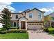 Charming two-story home with a well-manicured front yard, a brick driveway, and a two-car garage at 1421 Wexford Way, Davenport, FL 33896