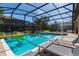 Relaxing screened-in pool area with inviting lounge chairs, blue tile, and a lovely yard at 1421 Wexford Way, Davenport, FL 33896