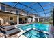 The screened-in pool area showcases a spa, chairs for lounging, and access to the covered patio at 1421 Wexford Way, Davenport, FL 33896