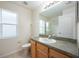 Modest bathroom featuring a single sink vanity, standard toilet, and a large window at 15309 Markham Dr, Clermont, FL 34714