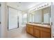 Bright bathroom featuring a double sink vanity, large mirror, and a glass-enclosed tub-shower combination at 15309 Markham Dr, Clermont, FL 34714