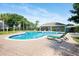 Community pool featuring a blue tiled pool, a pool house, lounge chairs, and lush landscaping at 15309 Markham Dr, Clermont, FL 34714