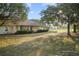 Inviting exterior elevation with a covered porch, manicured bushes, and mature trees for a welcoming curb appeal at 16017 Johns Lake Rd, Clermont, FL 34711