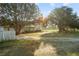 A beautiful view of a home's well-maintained front yard, with large trees, and a charming white picket fence at 16017 Johns Lake Rd, Clermont, FL 34711