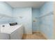 Laundry room with a washer, dryer, overhead shelves, and tile flooring at 16017 Johns Lake Rd, Clermont, FL 34711
