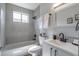 Well-lit bathroom featuring a shower over tub, neutral tile surround, and updated vanity at 221 E Fern Dr, Orange City, FL 32763