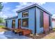 Modern blue home featuring a stylish exterior with a black roof, wood accents, and a charming front yard flower bed at 221 E Fern Dr, Orange City, FL 32763