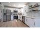 Bright modern kitchen with white cabinets, stainless steel appliances, and light wood floors at 221 E Fern Dr, Orange City, FL 32763