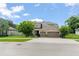 Large two-story home featuring well-manicured lawn, mature trees, and a three-car garage for ample parking at 2401 Oxmoor Dr, Deland, FL 32724