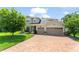 Charming two-story home with a brick driveway, a manicured lawn, and a three-car garage at 2401 Oxmoor Dr, Deland, FL 32724