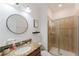 Bright bathroom featuring a granite vanity, glass-enclosed shower, and round mirror at 2923 Banana Palm Dr, Kissimmee, FL 34747