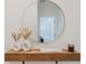 Close-up of an entryway with stylish decor, round mirror, and floating wood shelf at 2923 Banana Palm Dr, Kissimmee, FL 34747