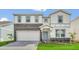 Two-story home with stone accents, a well-maintained lawn, and a paved driveway leading to a two-car garage at 3082 Mahalo Dr, Davenport, FL 33897