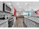 Contemporary kitchen with gray cabinetry, stainless steel appliances, granite countertops, and open access to the living room at 3082 Mahalo Dr, Davenport, FL 33897