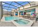 A screened in pool and spa is adjacent to an outdoor kitchen and seating area in this home's backyard at 3082 Mahalo Dr, Davenport, FL 33897