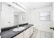 Well-lit bathroom featuring a large mirror and a white sink with a black countertop at 3304 Vancouver Ave, Deltona, FL 32738