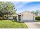 Charming single-story home featuring an attached two car garage and mature trees in the front yard at 3304 Vancouver Ave, Deltona, FL 32738