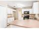 Functional kitchen featuring white cabinets, a black microwave and range and views of the adjacent rooms at 3304 Vancouver Ave, Deltona, FL 32738