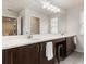 Bathroom with dual sinks, long vanity with stylish wood cabinets, vanity seating, and a large frameless mirror at 3804 Corona Ct, Sanford, FL 32773