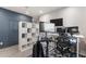 Home office with multiple monitors and workout bike with modern white shelving and blue accent wall at 3804 Corona Ct, Sanford, FL 32773